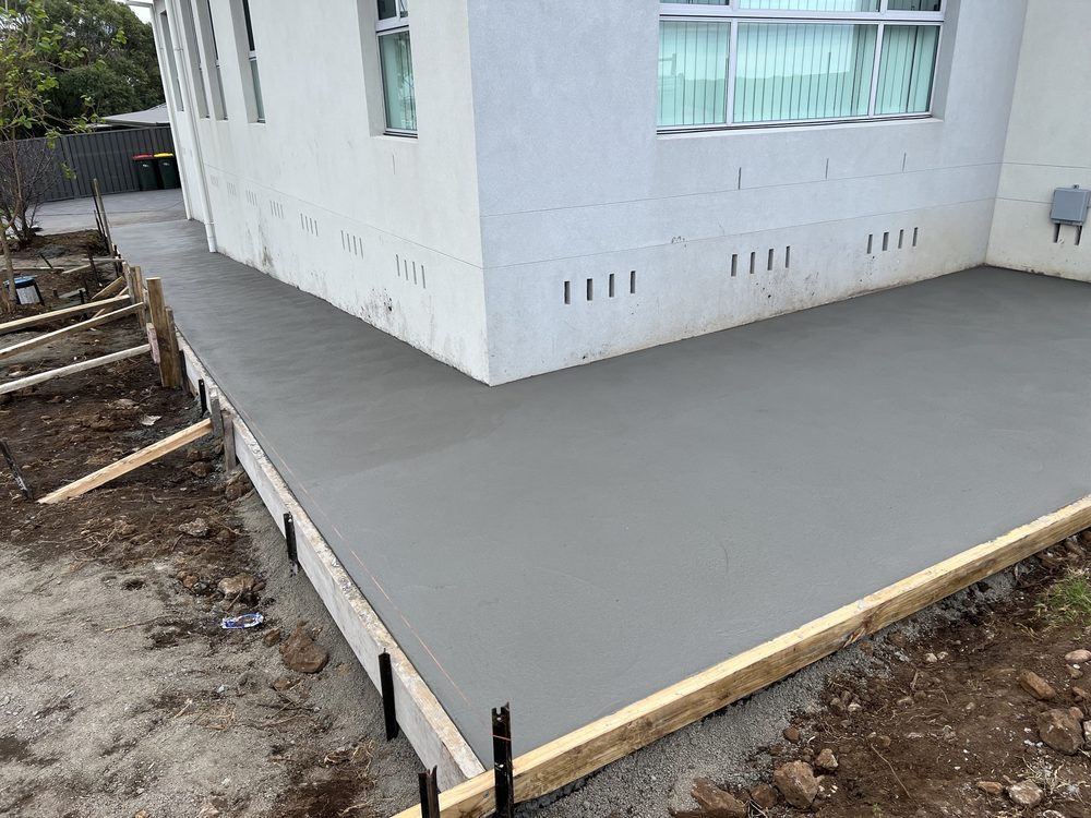 Freshly poured concrete slab beside a rendered home
