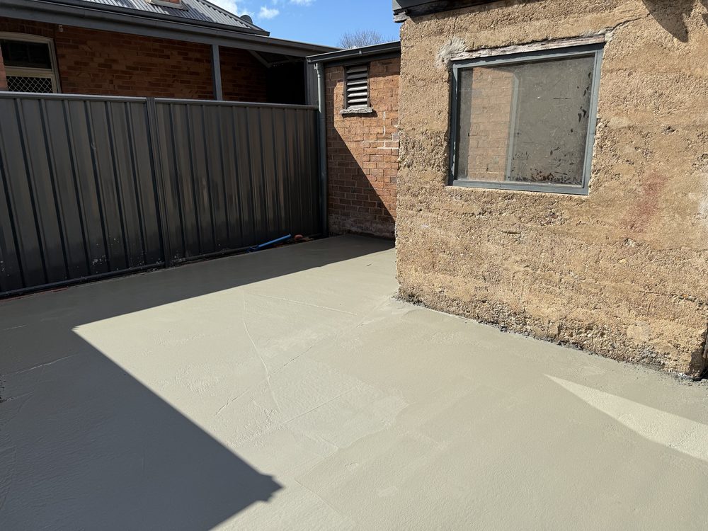 Concrete patio poured beside a heritage brick home